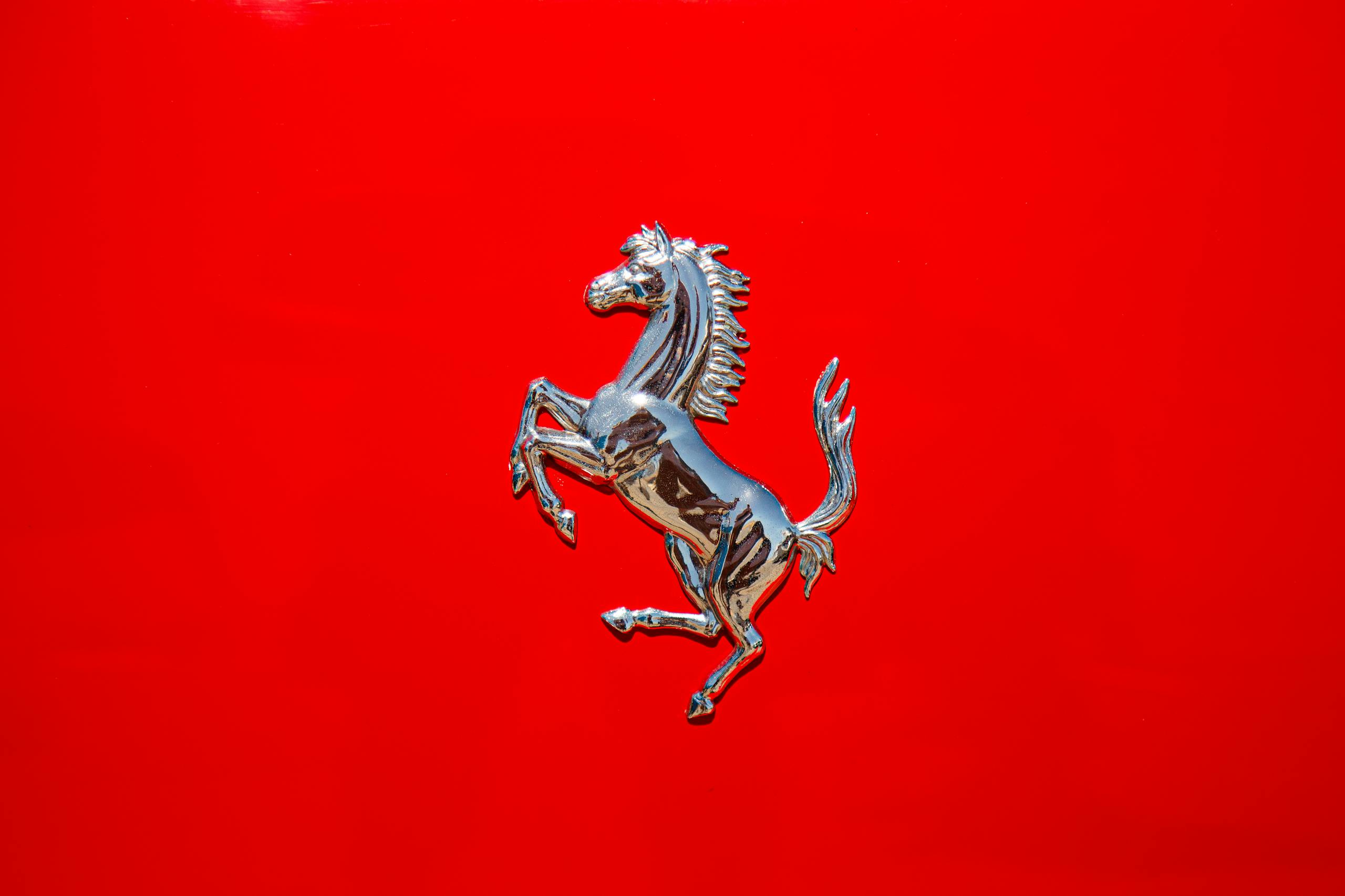 Close-up of a luxury car emblem on a glossy red surface displaying elegance and style.